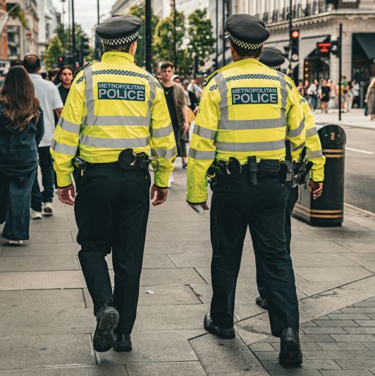 Rear view of 2 Metropolitan Police Officers patrolling the streets
